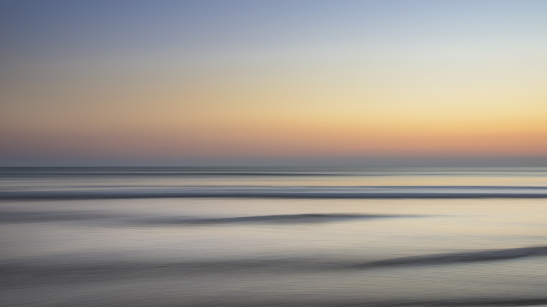 Une mer calme au petit matin, l’horizon dégagé sous un ciel qui s’éclaircit.