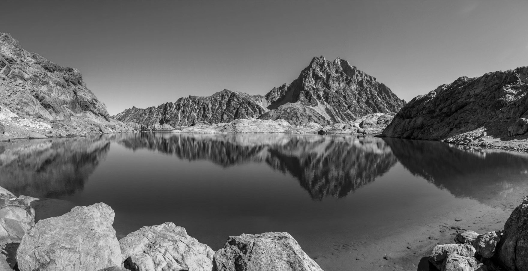 Un sommet parfaitement reflété dans un lac de montagne immobile.